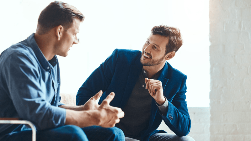 Two male colleagues demonstrate active listening through open and positive body language