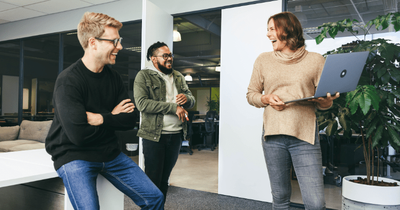 three smiling colleagues exhibiting the impact of effective team dynamics