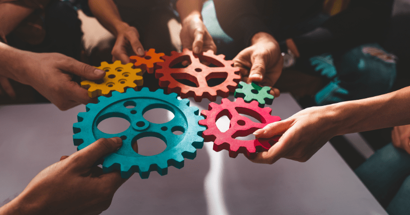 Team holding cogs together to symbolise the power of collaboration